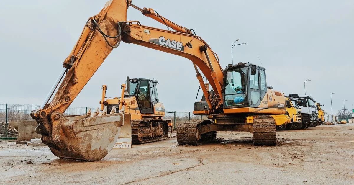 Excavatrice garée sur un chantier montrant des machines lourdes et des travaux industriels.