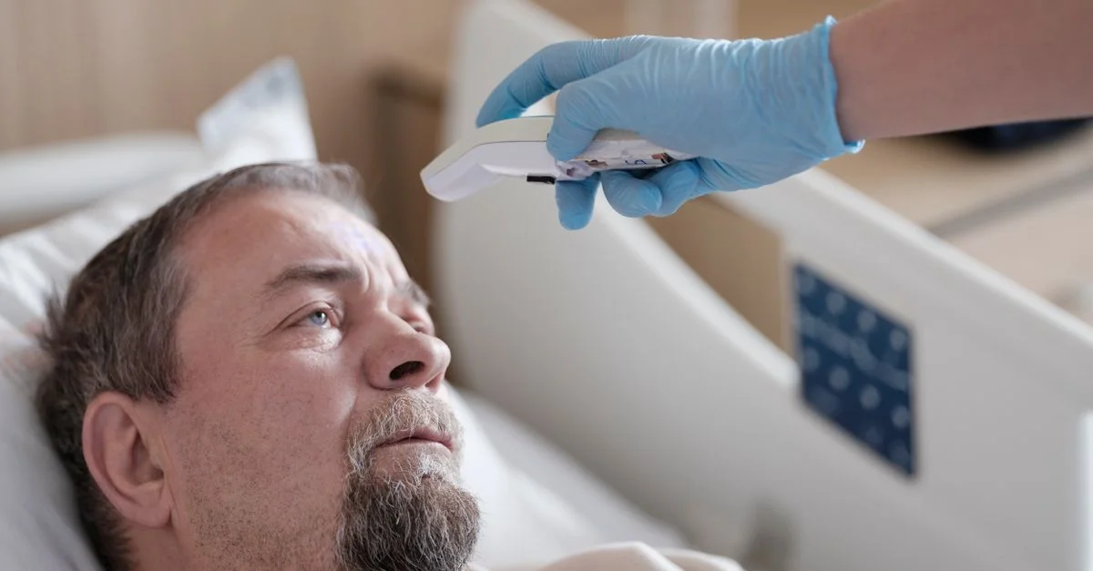 Un professionnel de la santé mesure la température d'un patient à l'aide d'un thermomètre sans contact dans un cadre hospitalier.