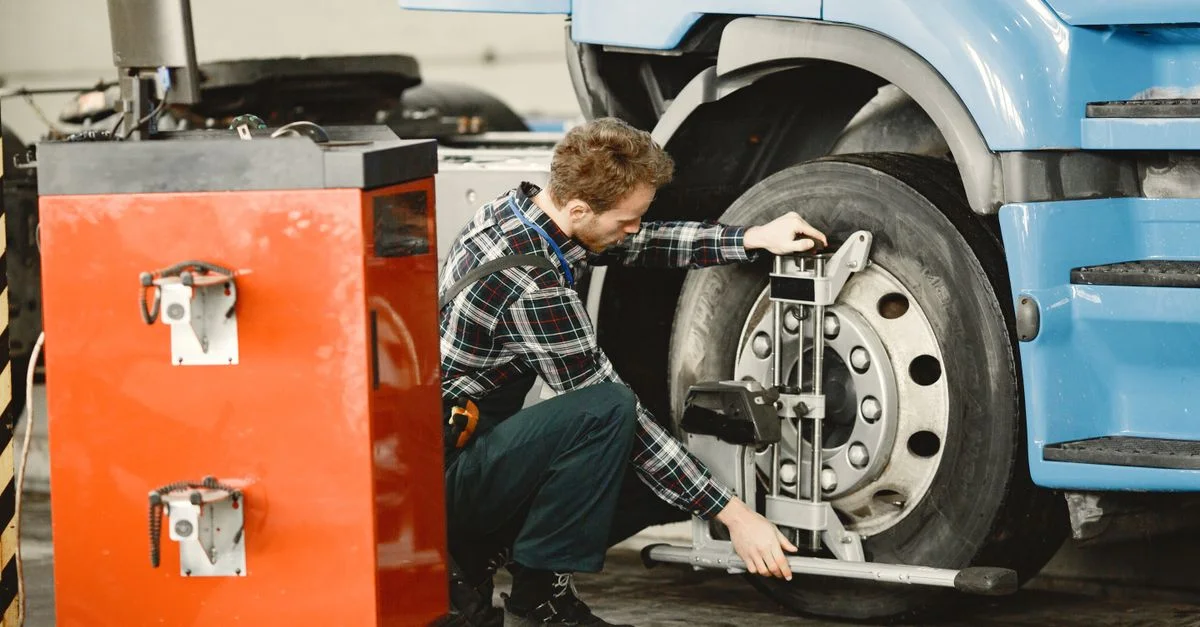 Un mécanicien effectuant un réglage de pneus sur un camion dans un atelier intérieur.