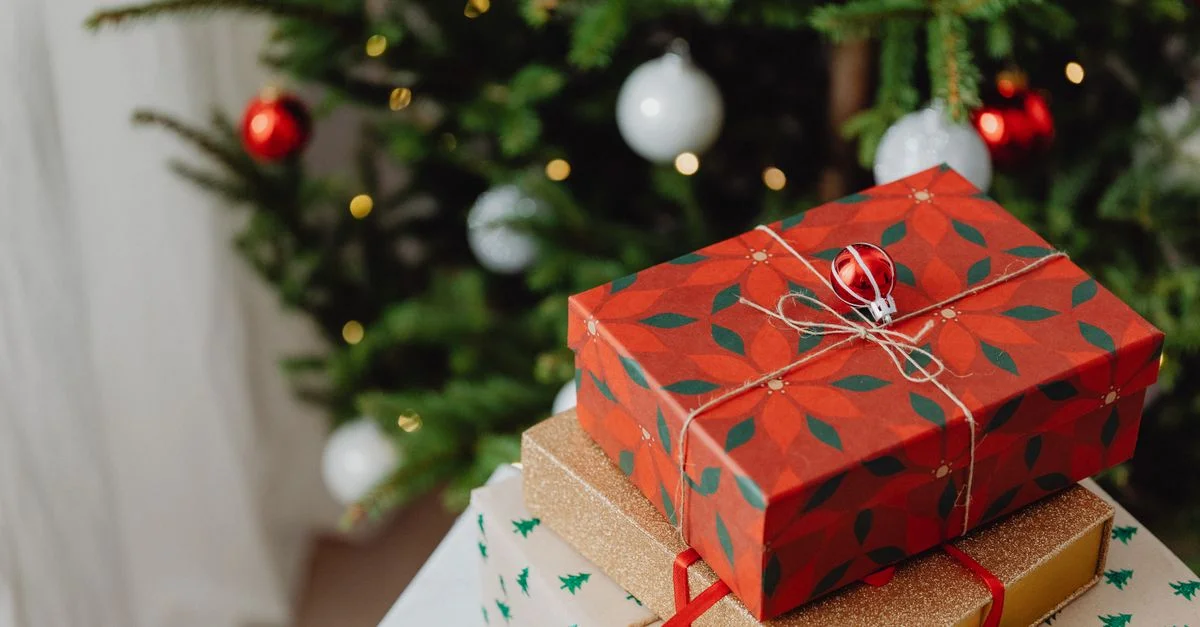Cadeaux de Noël magnifiquement emballés sous un arbre avec des lumières.
