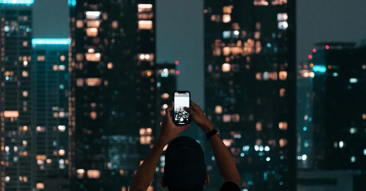 Une personne photographiant les gratte-ciel illuminés de Jakarta lors d'une nuit animée de la ville.