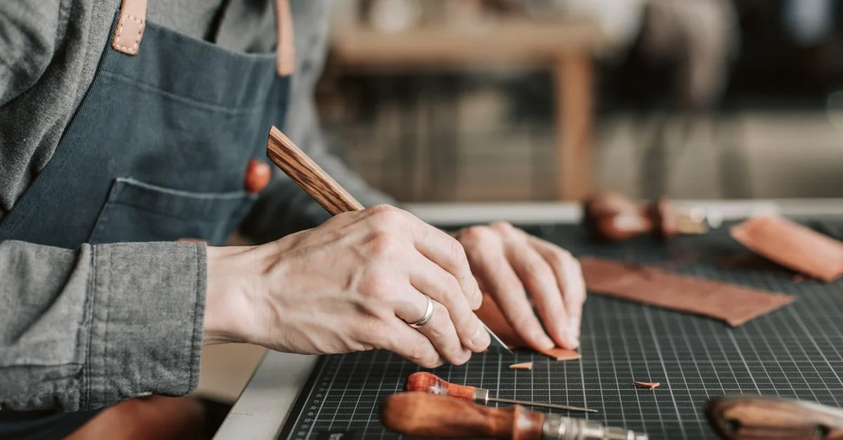 Gros plan d'un artisan créant habilement des articles en cuir à la main dans un atelier.
