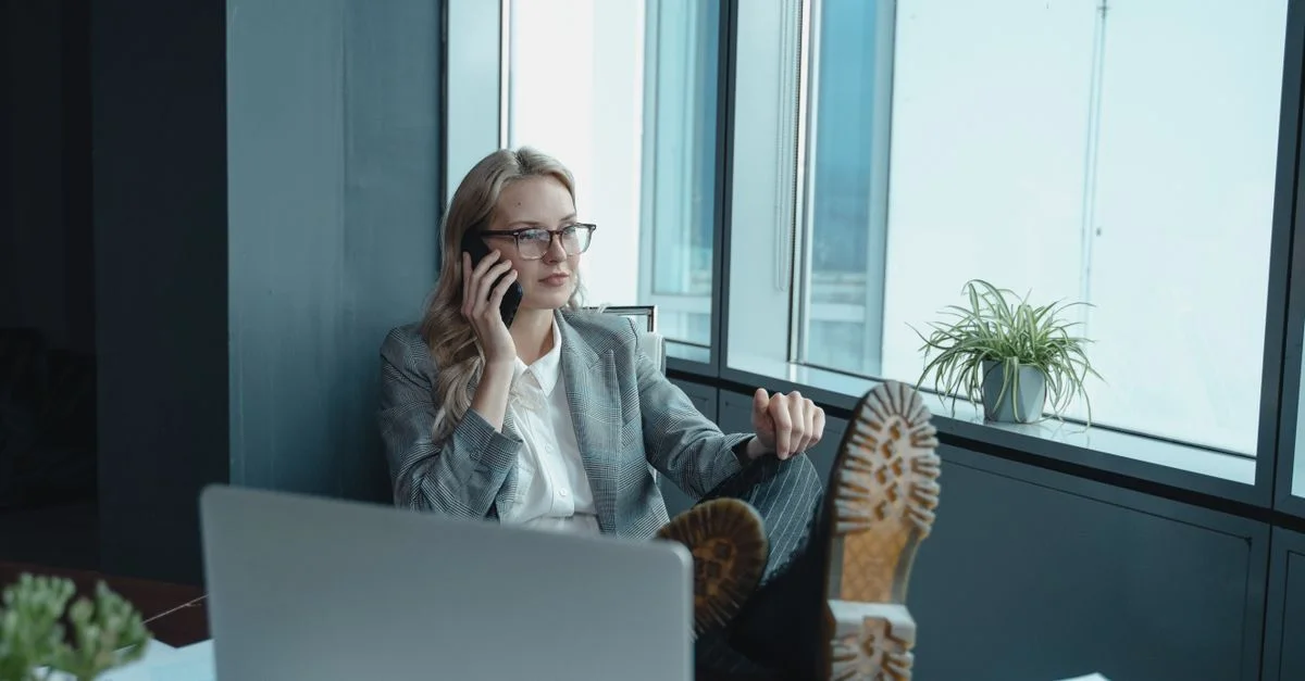 Femme professionnelle dans un bureau, détendue mais concentrée, en train de passer un appel.