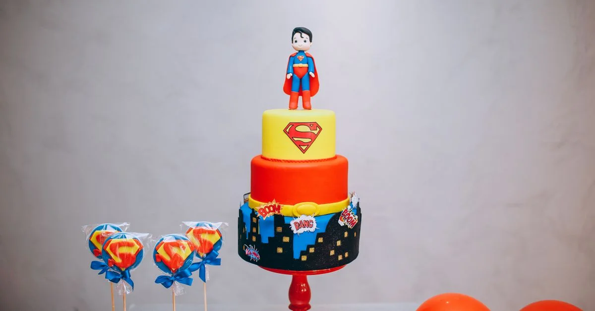 Gâteau Superman vibrant avec des décorations sur le thème des super-héros et des ballons.